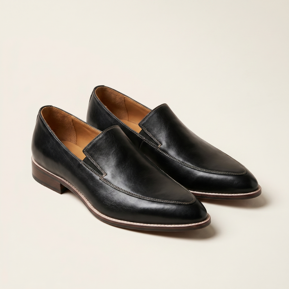 Black leather slip on loafers with contrast stitching and a tan toned sole