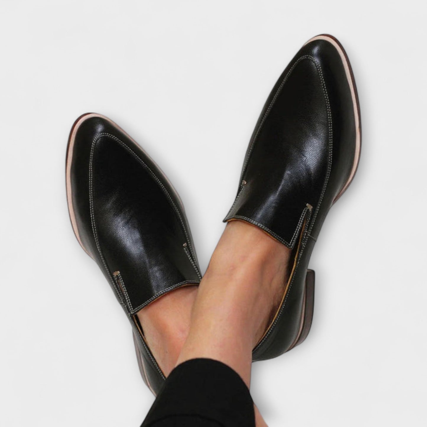 Black leather slip on loafers with contrast stitching and a tan toned sole