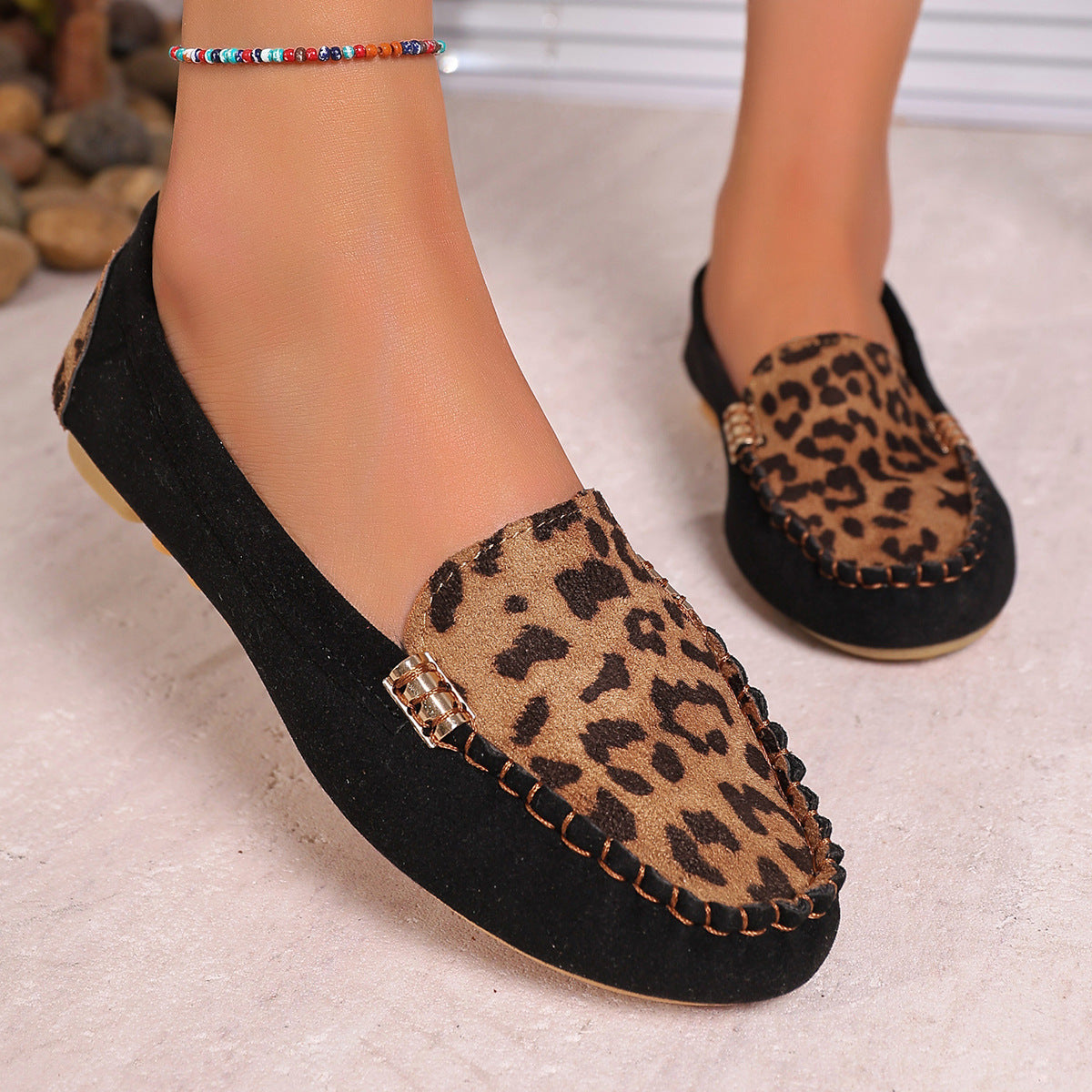 Brown leopard print moccasin loafers with decorative stitching and a studded sole
