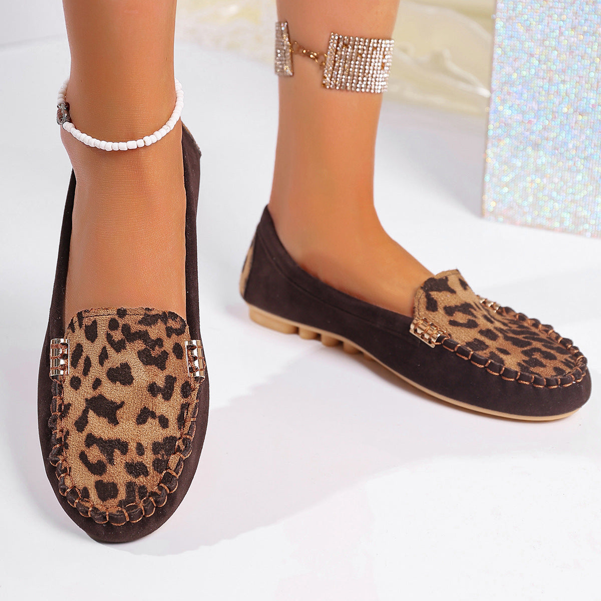 Brown leopard print moccasin loafers with decorative stitching and a studded sole