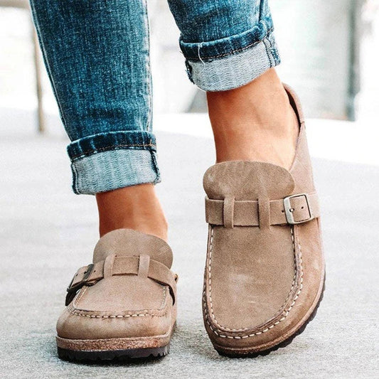 Khaki suede loafer mules with a buckle strap and a cork footbed
