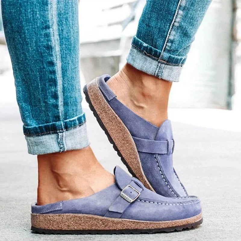Khaki suede loafer mules with a buckle strap and a cork footbed