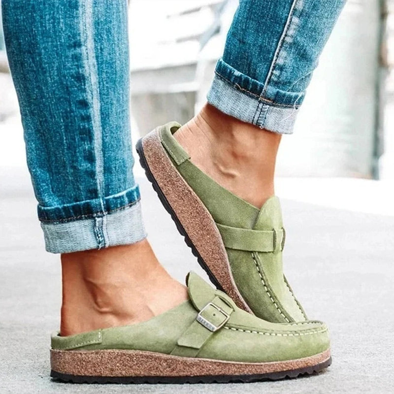 Khaki suede loafer mules with a buckle strap and a cork footbed
