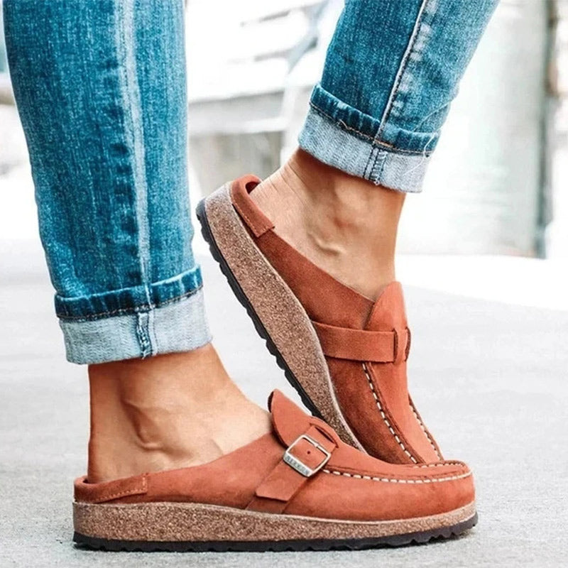 Khaki suede loafer mules with a buckle strap and a cork footbed